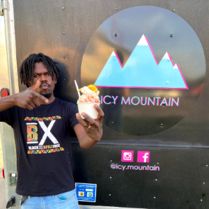 Man holding snow cone in front of Icy Mountain food truck.