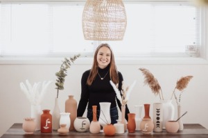 Terra Therapi smiling behind table full of vases