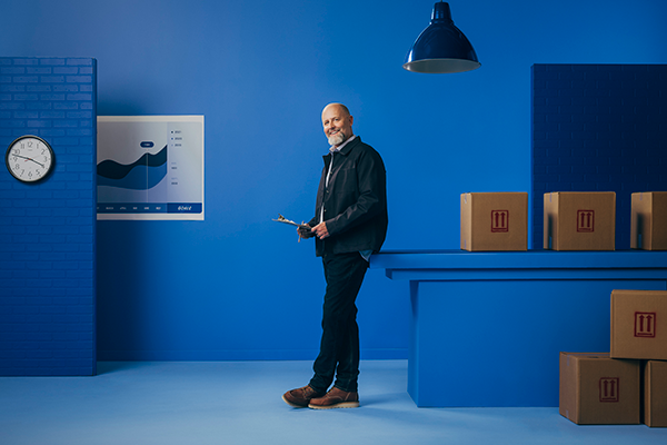 Man standing and holding clip board in work room with boxes.