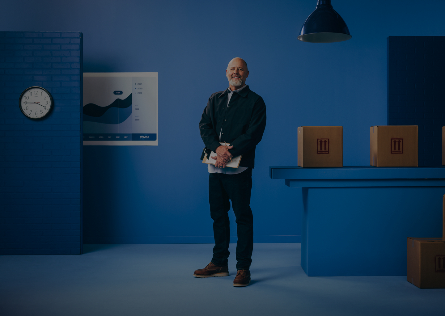 Man smiling and holding clipboard in work room with boxes