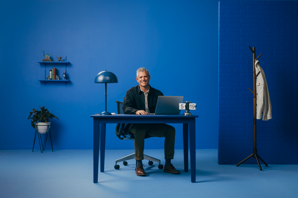 Man smiling while sitting behind desk with laptop.