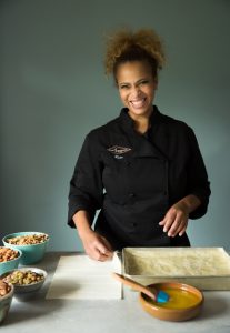 Rita Magalde, owner of Sheer Ambrosia Bakery, smiling while baking