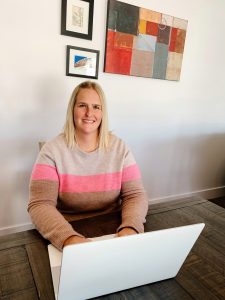 Allie Blackham smiling while work on laptop at desk