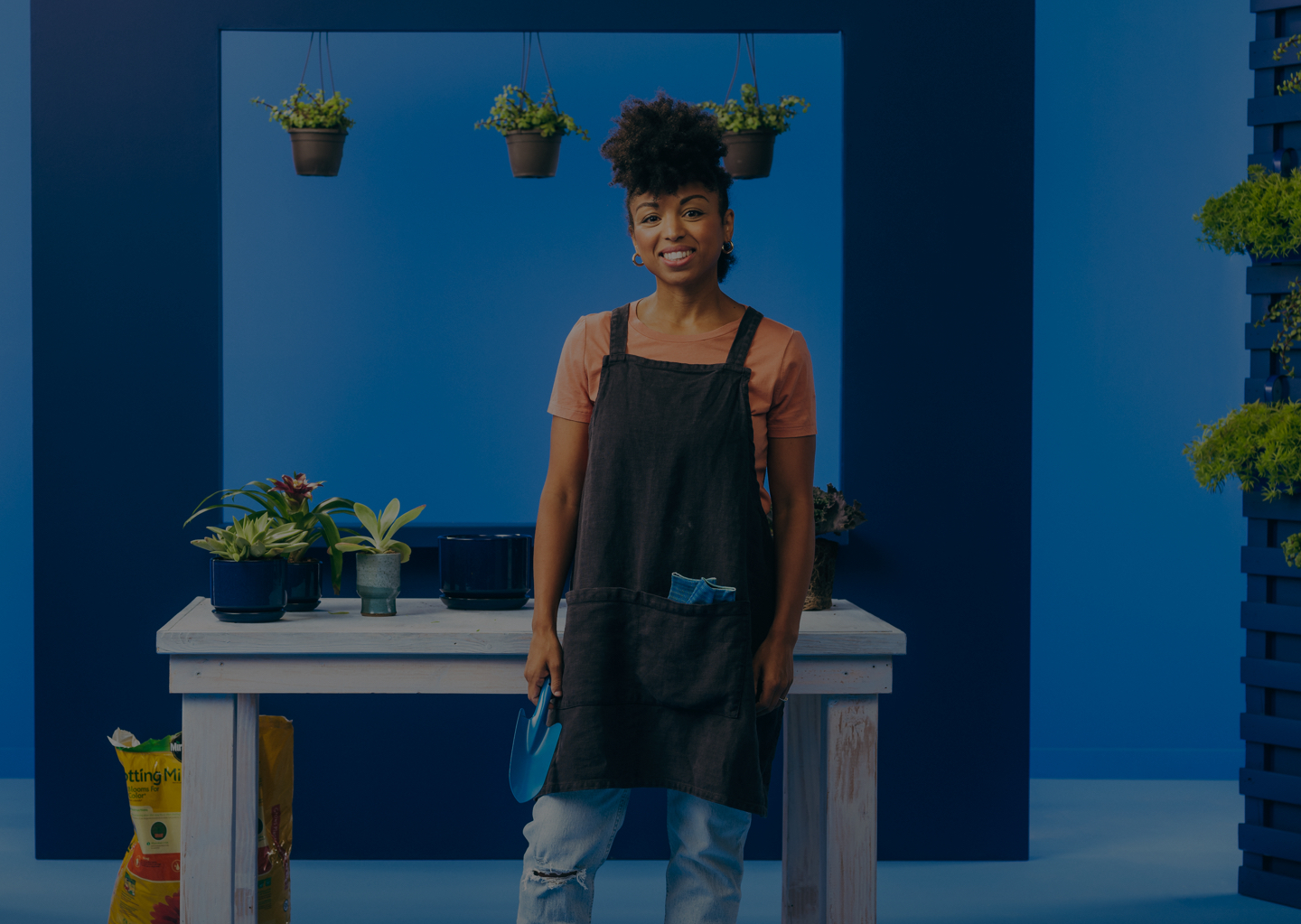 Woman in apron smiling in greenhouse