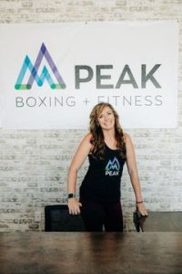 Woman smiling behind table in PEAK Boxing + Fitness studio