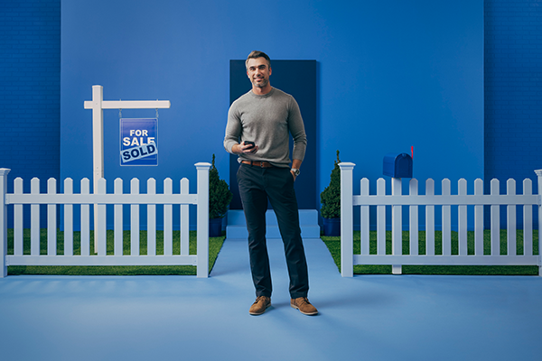 Man standing insetting that shows a "home sold" sign